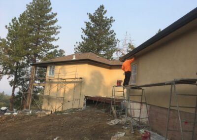 long view of house construction project of tlb builder two men are painting